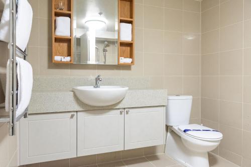bagno con lavandino, servizi igienici e specchio di Ocean Breeze Hotel ad Auckland