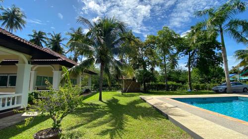 a villa with a swimming pool and palm trees at Palm Gardens Resort, Bang Saphan in Bang Saphan