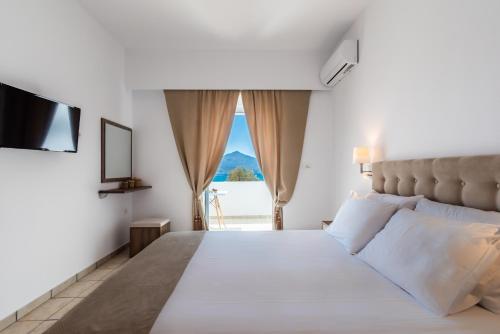 sypialnia z dużym białym łóżkiem i oknem w obiekcie Play On The Sand w mieście Adamas