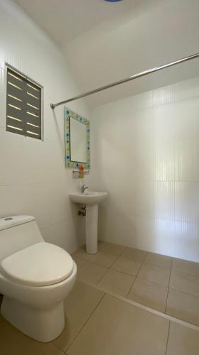 a white bathroom with a toilet and a sink at Palm Gardens Resort, Bang Saphan in Bang Saphan