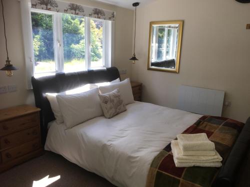 1 dormitorio con 1 cama con sábanas y almohadas blancas en Woodland Cabin With private Wood-Fired Hot-Tub en Farnham