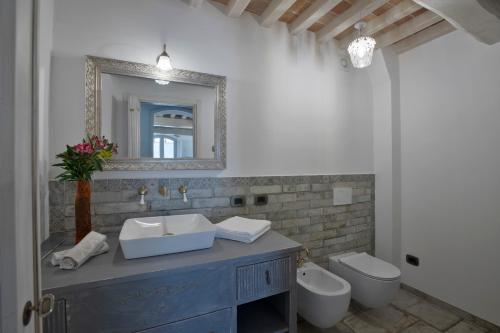 Un baño con lavabo, espejo e inodoro. en Agriturismo Alchimista, en Casole dʼElsa