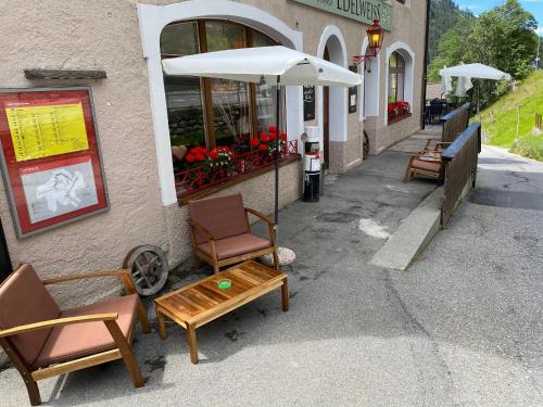 eine Gruppe von Stühlen und Tischen außerhalb eines Gebäudes in der Unterkunft Gasthaus Edelweiss in Langwies
