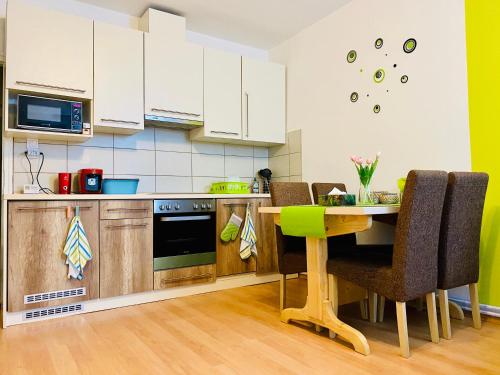 a kitchen with white cabinets and a table with chairs at Kálvária Apartman Szeged in Szeged