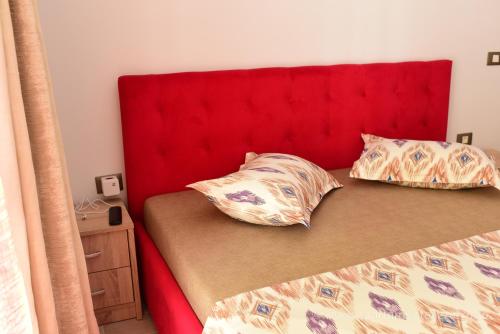 a bed with a red headboard and two pillows on it at Apartamente Azzurro on the beach in Mamaia Sat/Năvodari