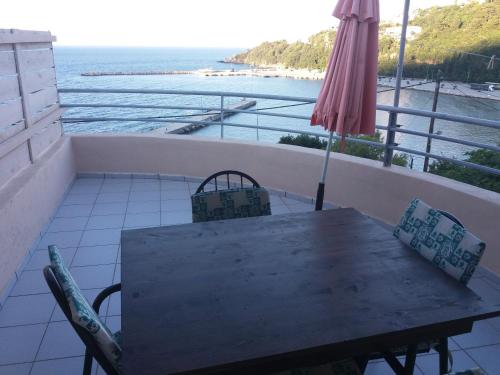 a table and chairs on a balcony with an umbrella at Harbour View - Oceanis Apartments in Poros