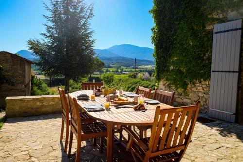 une table en bois avec des chaises assises sur une terrasse dans l'établissement Ermitage Crestet (Ventoux - Provence), à Crestet