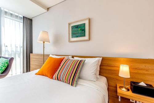 a bedroom with a white bed with a wooden headboard at Jeju Bom stay & Art Gallery in Seogwipo