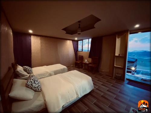 a hotel room with two beds and a large window at Petra Wassaif Camp in Wadi Musa