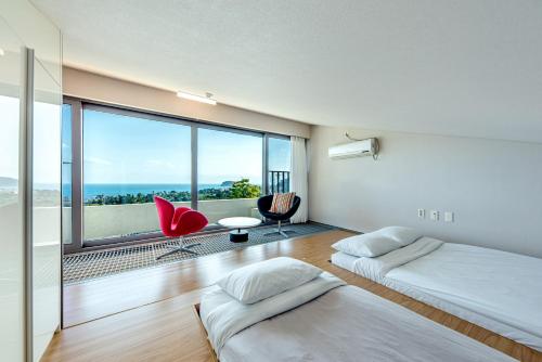 a bedroom with two beds and a large window at Jeju Bom stay & Art Gallery in Seogwipo