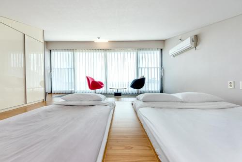 two beds in a room with two chairs and a table at Jeju Bom stay & Art Gallery in Seogwipo