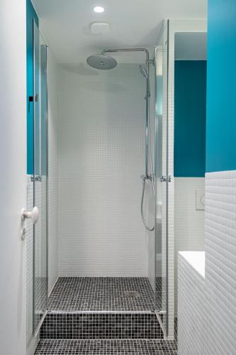 une douche avec une porte vitrée dans une salle de bain dans l'établissement NEW - Superbe 1 Bdr Appt - Design 60'S - Paris 15e, à Paris