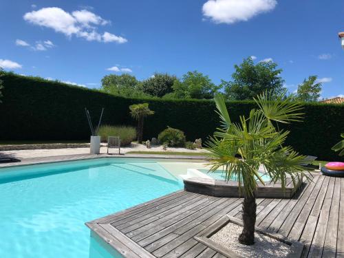 una piscina con una palmera junto a una terraza de madera en Guesthouse proche bordeaux, en Eysines
