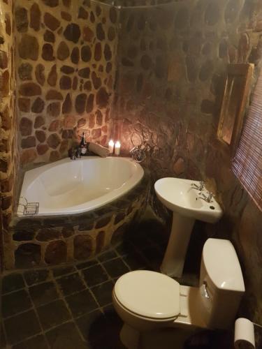 a stone bathroom with a tub and a toilet and a sink at umbabala bush camp in Rustenburg