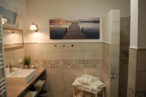 ein Badezimmer mit einem Waschbecken und einem Bild eines Piers in der Unterkunft Weingut Krikler in Weiden am See