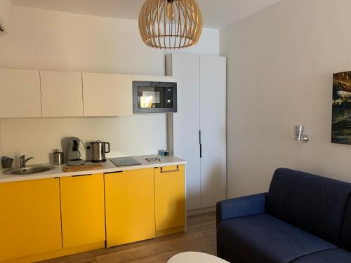 une cuisine avec des armoires jaunes et un canapé bleu dans l'établissement Studio terrasse rue piétonne Ajaccio, à Ajaccio