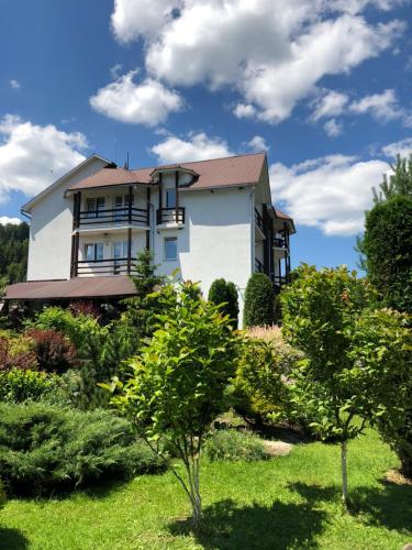 a large white house with trees in the yard at Smerekovyi Dvir in Zhdenievo