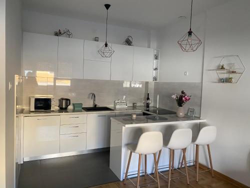 a kitchen with white cabinets and bar stools at Harmony Suite in Trebinje