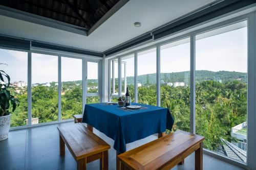 a dining room with a table and benches and windows at Brenta Phu Quoc Hotel in Phu Quoc