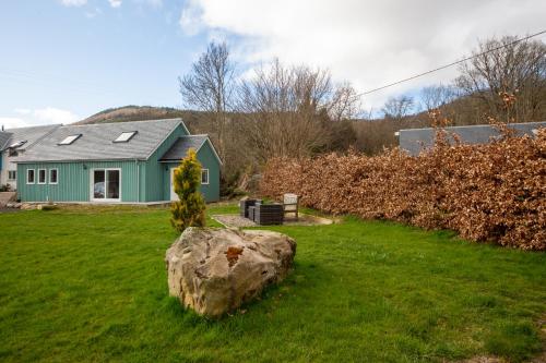 a green house with a rock in the yard at The GREENHOUSE in Aberfeldy