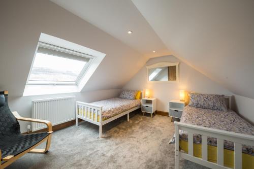 a attic bedroom with two beds and a window at The GREENHOUSE in Aberfeldy