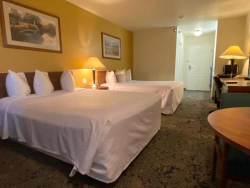 een hotelkamer met twee bedden met witte lakens bij Rodeway Inn Salina North in Salina