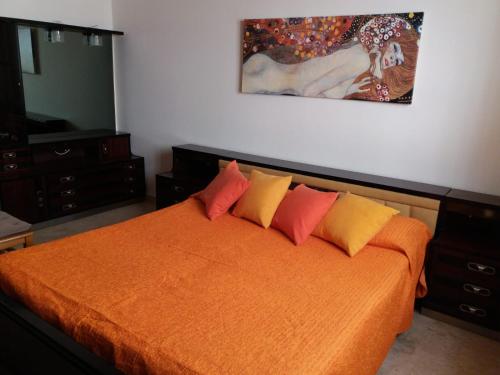 1 dormitorio con 1 cama con sábanas y almohadas de color naranja en Appartamento vicino al mare en Giardini Naxos