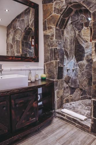 a stone bathroom with a sink and a mirror at Sansara Surf Yoga & Resort in Cambutal