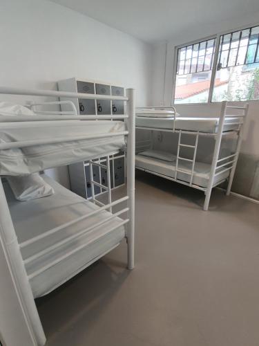 a room with three bunk beds and a window at ALBERGUE DE CALDAS de REIS Peregrinos y Turistico in Caldas de Reis