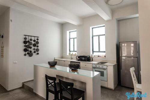a white kitchen with a counter and a refrigerator at YalaRent Boutique Apartments in Jaffa's Flea Market in Tel Aviv