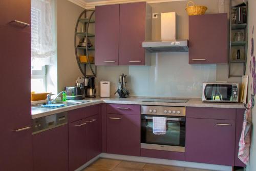 een keuken met paarse kasten en een magnetron bij Ferienhaus Nienhagen - Jule in Ostseebad Nienhagen