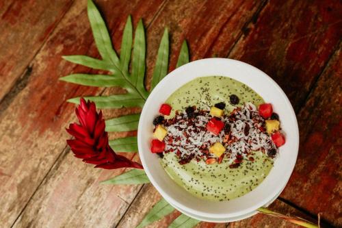 a bowl of soup with cereal and fruit on a wooden table at Sansara Surf Yoga & Resort in Cambutal