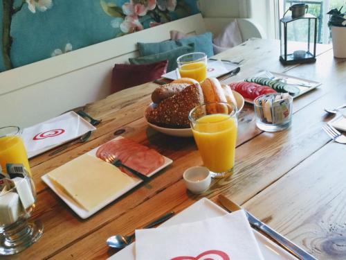 una mesa de madera cubierta con un plato de comida y zumo de naranja en Yxningens Holiday Homes, Cottages and Camping, en Gusum