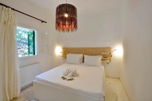 a bedroom with a bed with white sheets and a chandelier at Minimalist Cozy House in Corfu