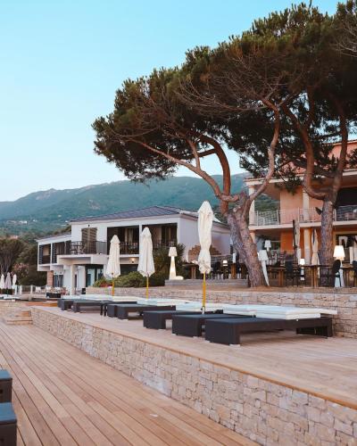 a row of tables with umbrellas in front of a building at Hôtel Castel d'Orcino in Calcatoggio