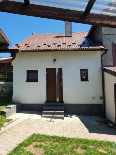 a small white house with a red roof at Domek Nad Czorsztynem in Mizerna