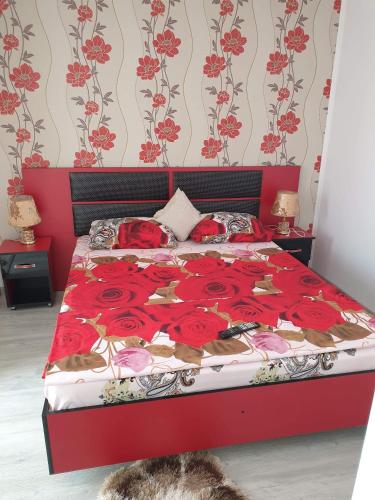 a red bed with red roses on it in a bedroom at Apartament Alina in Saturn