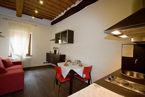 uma cozinha e sala de estar com uma mesa e um sofá vermelho em Vicolo dell'Oste em Montepulciano