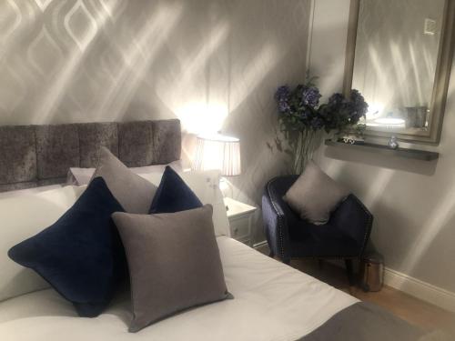 Un dormitorio con una cama con almohadas azules y una silla en Beechtree House en Dublín