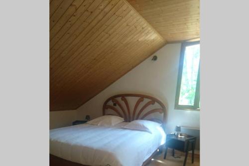 ein Schlafzimmer mit einem großen Bett und einer Holzdecke in der Unterkunft Studio entre lac et montagne in Attignat-Oncin