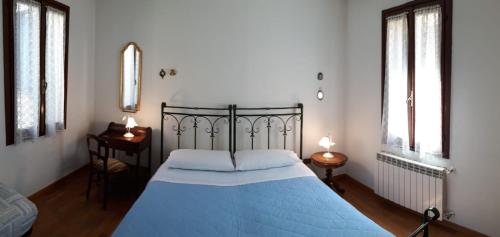 a bedroom with a blue bed and two windows at San Barnaba Artist's district house in Venice