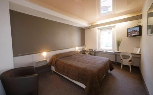 a bedroom with a bed and a desk and a window at Hôtel Le Lons in Foix