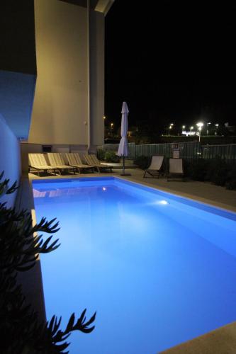 a swimming pool at night with blue illumination at Sun Apartments in Primošten