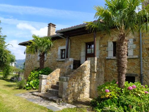 a stone house with a palm tree in front of it at La Rectoral in Beloncio