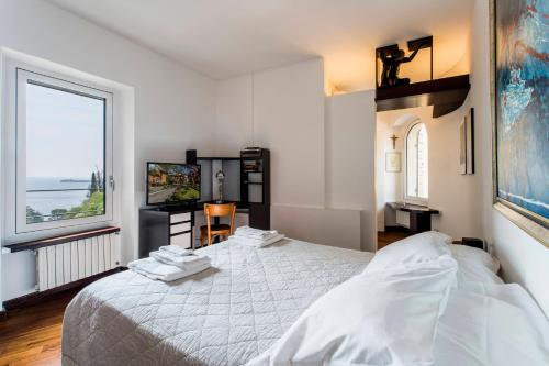 a bedroom with a white bed and a large window at Villa Glicine in Gardone Riviera