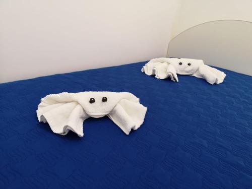 three stuffed elephants laying on a blue bed at Casetta "Le Due Palme" in Castellammare del Golfo