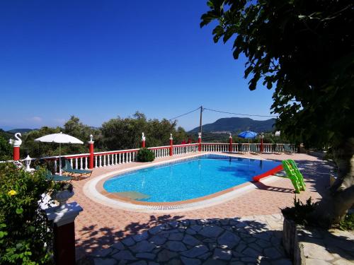 a large swimming pool with a red fence around it at Villa PANGALIS Romantica in Kato Pavliana
