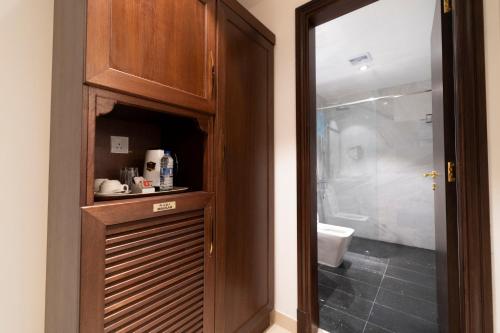 a bathroom with a shower and a wooden cabinet at Alhattali Hotel in Muscat