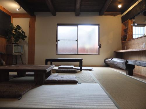 a room with a table and a bench and a window at YOMOGI GUESTHOUSE in Tokoname