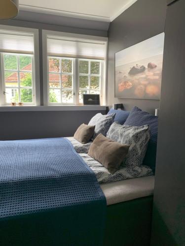 a bedroom with a bed with blue sheets and windows at Høyanger 3 roms leilighet in Høyanger